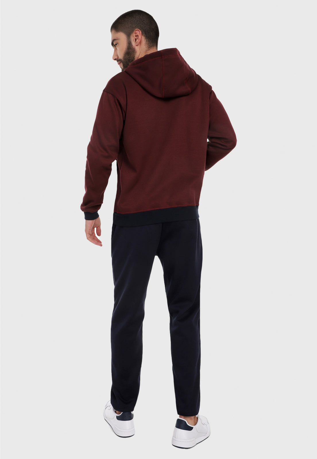 Hombre adulto visto de espalda vistiendo la sudadera para hombre conjunto chaqueta hoodie vinotinto con pantalón de sudadera azul.