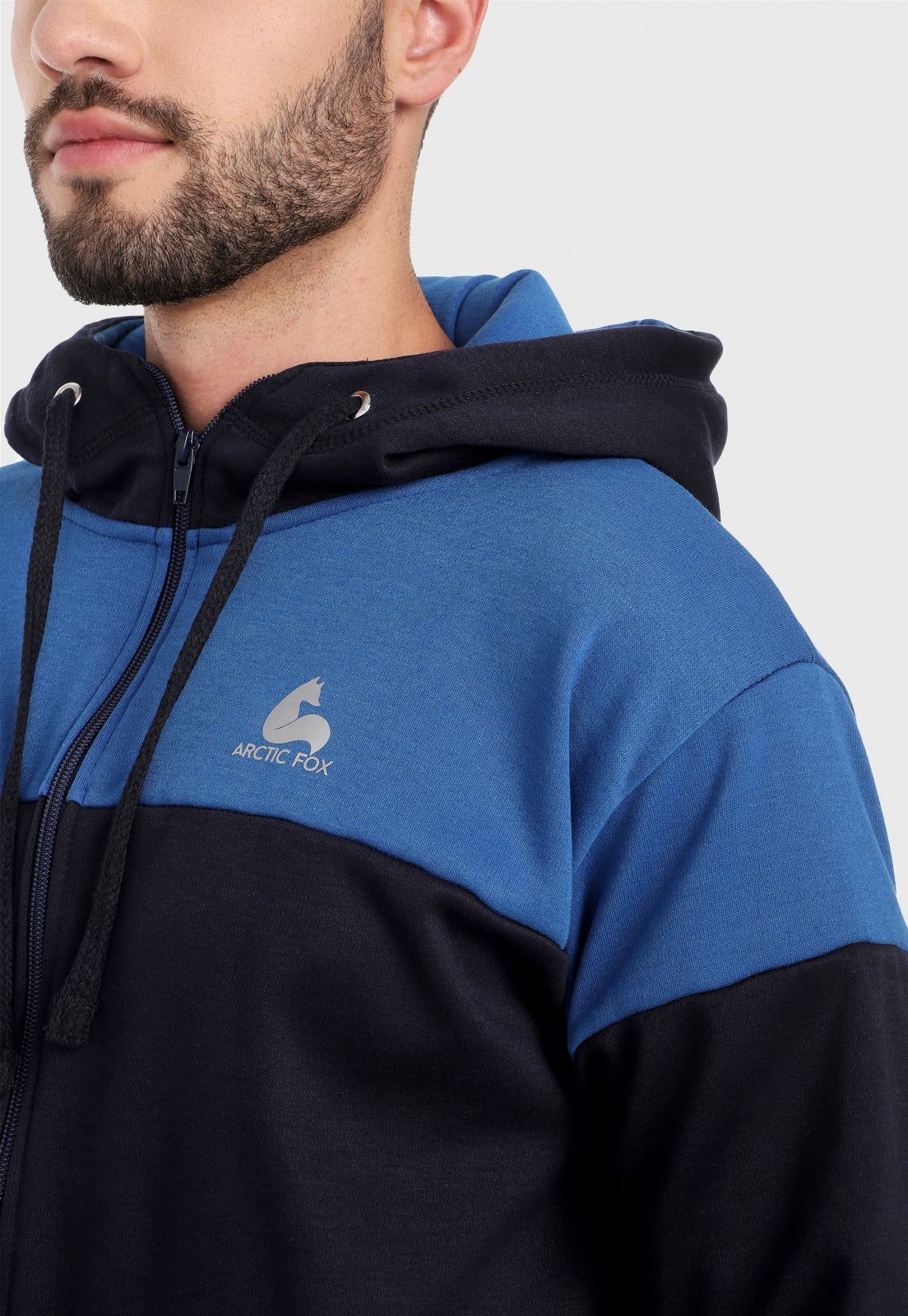 Detalle en buzo de hombre adulto vistiendo la sudadera para hombre conjunto chaqueta hoodie Azul Rey y Azul Obscuro con pantalón de sudadera azul obscuro.