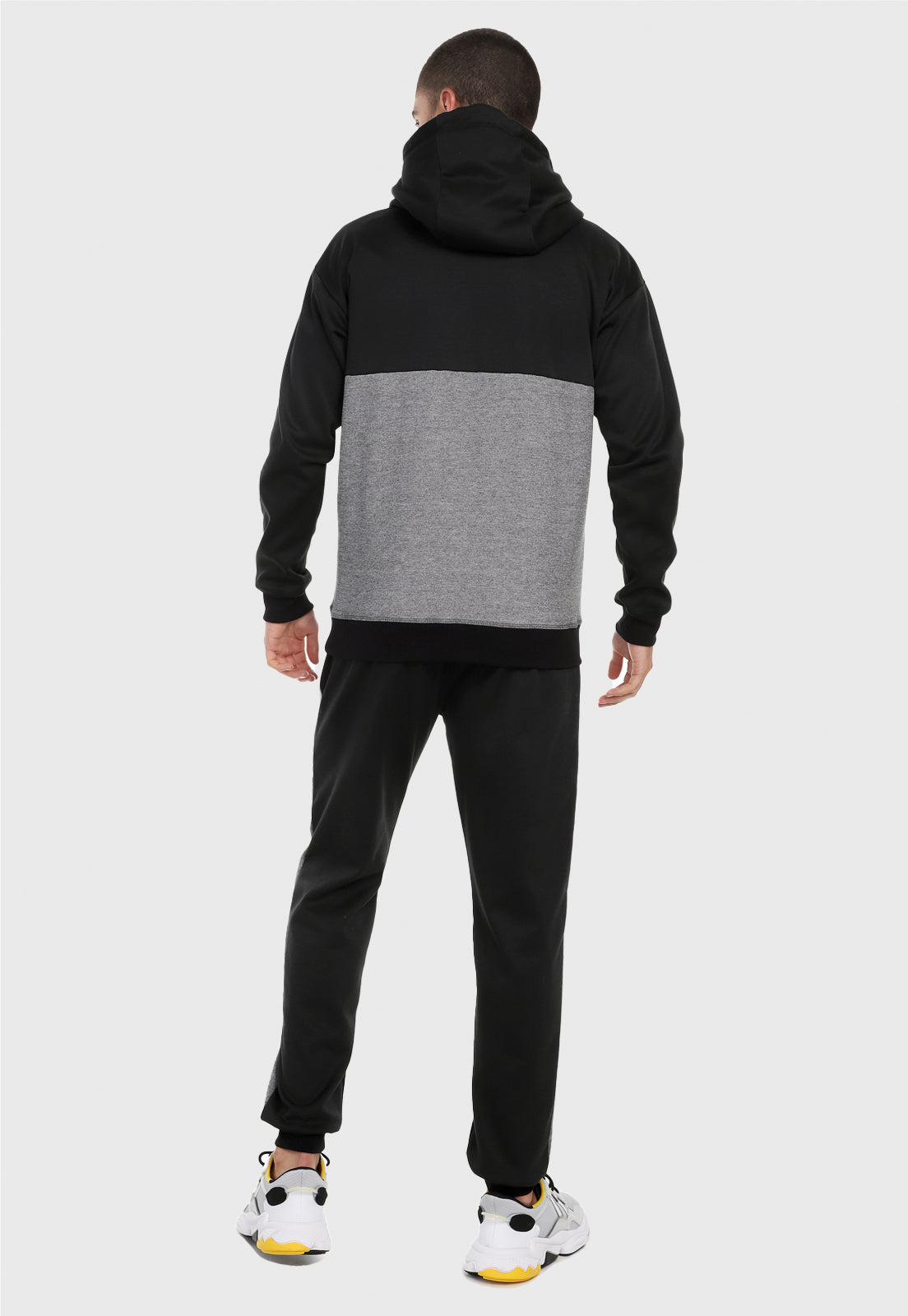 Hombre adulto visto de espalda vistiendo la sudadera para hombre conjunto buzo hoodie Negro y Gris  y pantalón de sudadera negro.