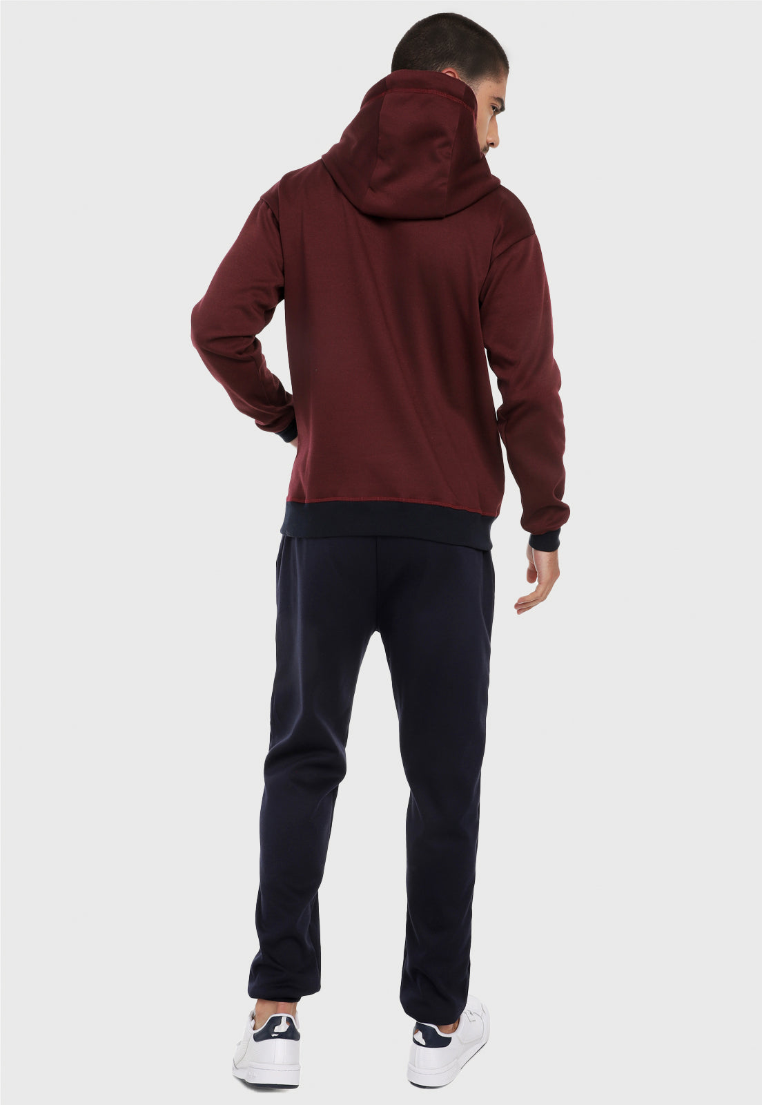 Hombre adulto visto de espalda vistiendo la sudadera para hombre conjunto buzo hoodie Vinotinto y Azul con pantalón de sudadera azul.