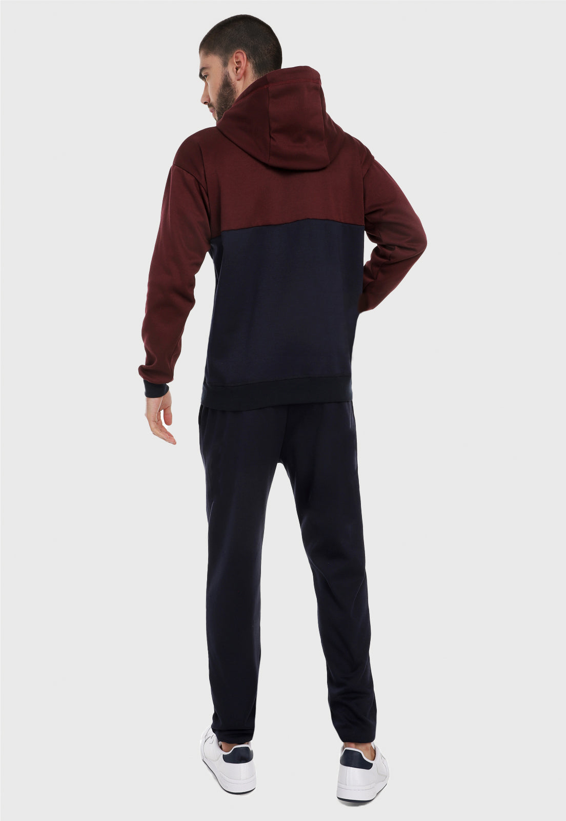 Hombre adulto visto de espalda vistiendo la sudadera para hombre conjunto buzo hoodie vinotinto y azul  y pantalón de sudadera azul.