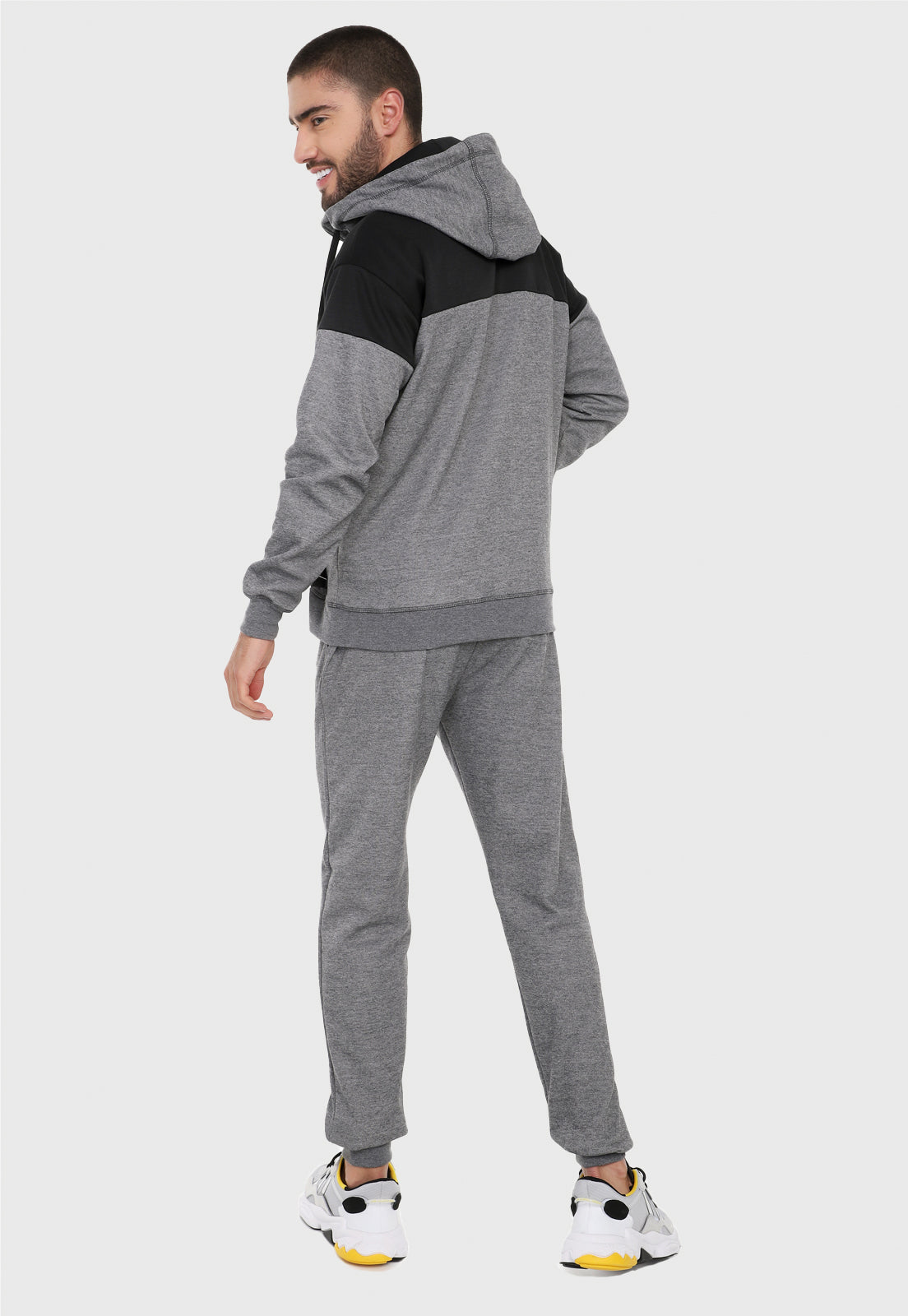 Hombre adulto de espalda vistiendo la sudadera para hombre conjunto chaqueta hoodie Gris y Negra corte americano con pantalón de sudadera gris.