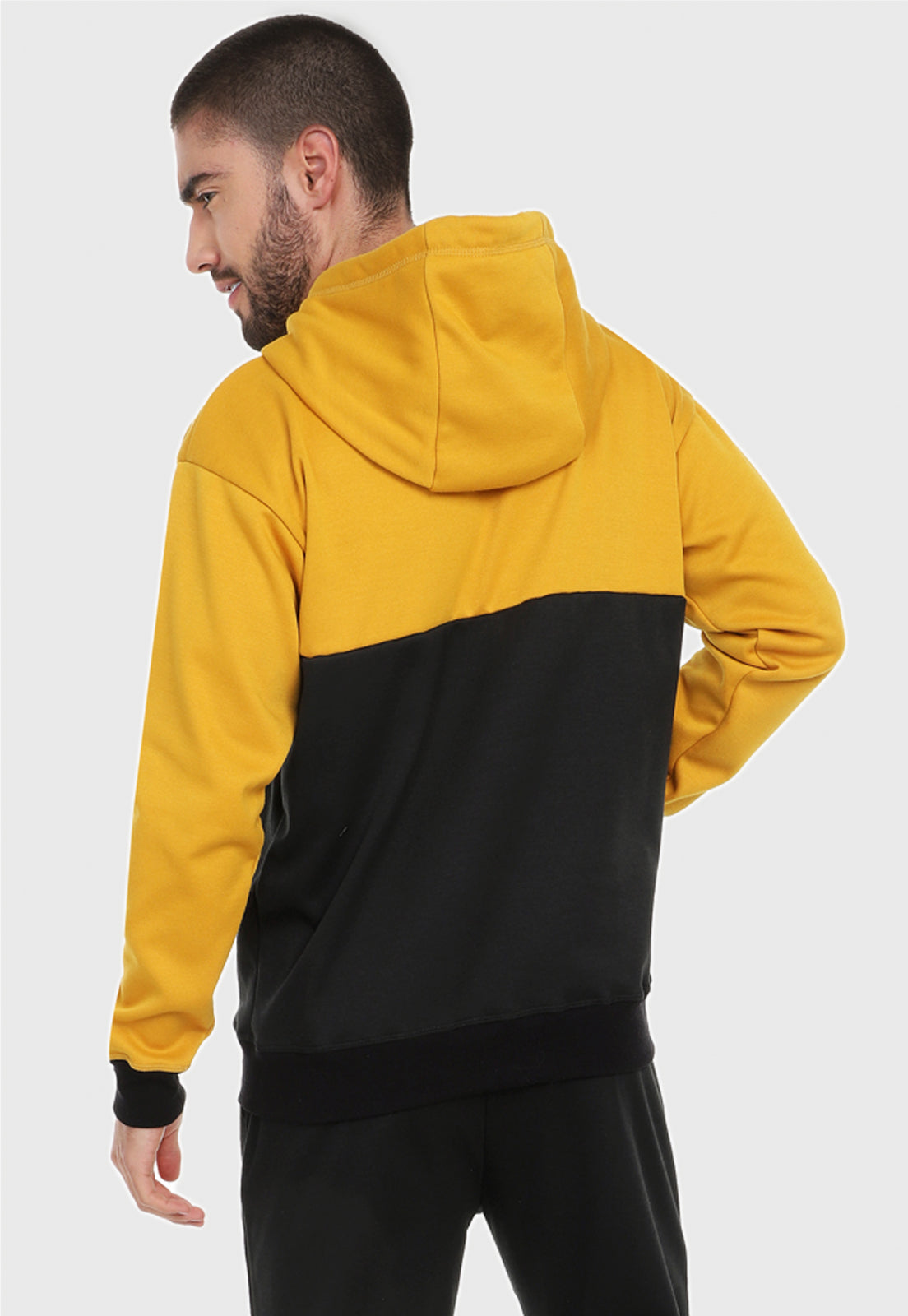 Detalle de hombre visto de espalda vistiendo el buzo hoodie mostaza y negro para hombre corte inglés.