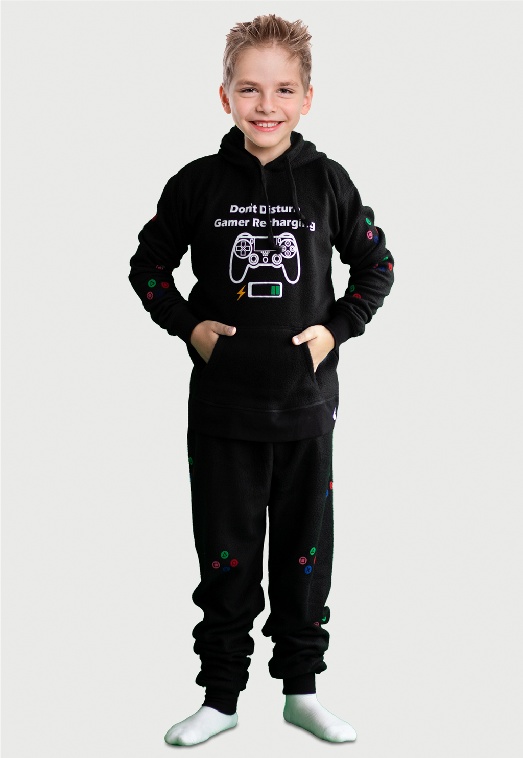 Niño vistiendo la Pijama para Niño Negra referencia Gamer Play con un control de gamer y el icono de batería cargando estampado en el pecho, en las mangas de pantalón y buzo van estampados los comando de juego en diferentes colores, diseño de Arctic Fox Colombia