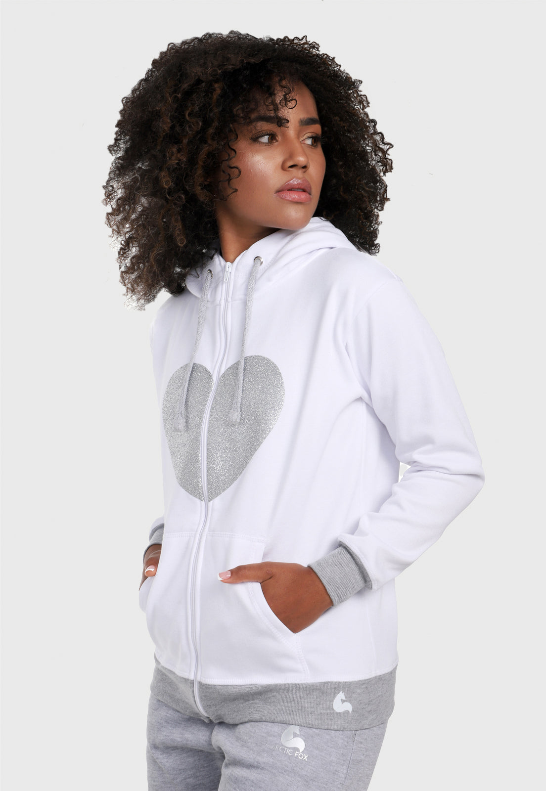 Mujer afro vistiendo la sudadera para mujer conjunto chaqueta hoodie blanco y gris con corazón brillante y pantalón de sudadera gris.