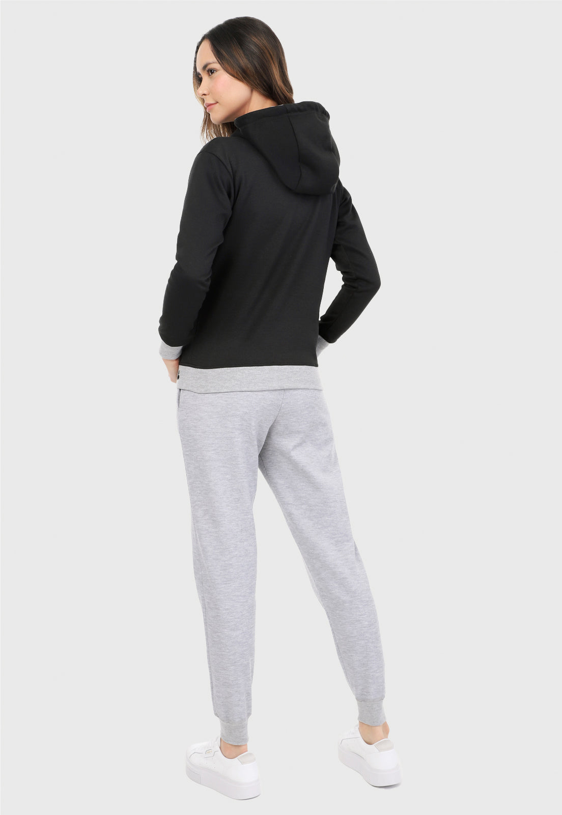 Mujer de espalda vistiendo la sudadera para mujer conjunto buzo hoodie color negro con corazón brillante y pantalón de sudadera gris.