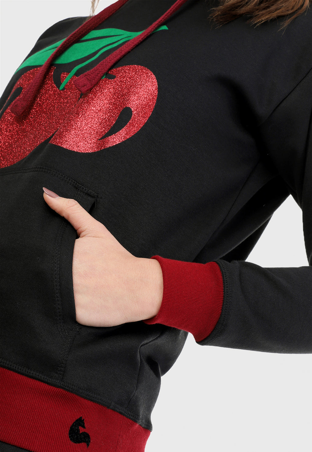 Detalle de mujer vistiendo la sudadera para mujer conjunto buzo hoodie negro con cerezas brillantes, ribs vinotinto en puño y cintura y pantalón de sudadera negro.