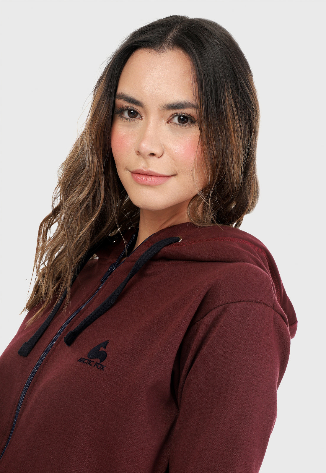 Detalle de mujer vistiendo la sudadera para mujer conjunto chaqueta hoodie vinotinto con capota forrada en azul al interior y pantalón de sudadera azul.