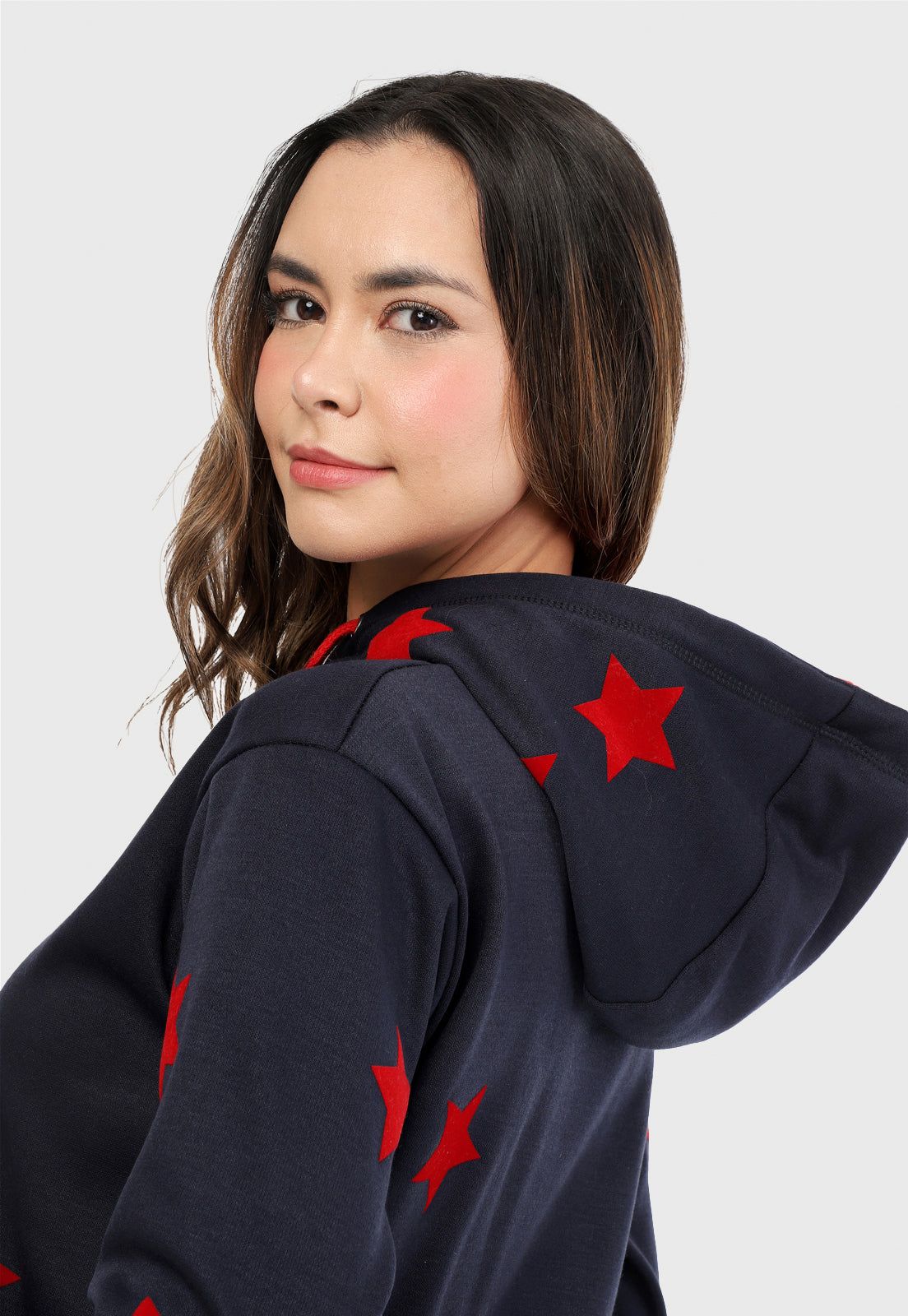 Detalle en capota de mujer vistiendo la sudadera para mujer conjunto buzo hoodie color azul con estrellas rojas y pantalón de sudadera negro.