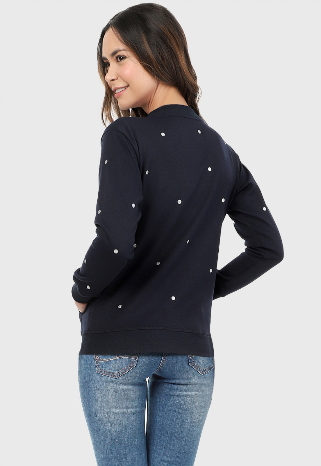 Mujer vista de espalda vistiendo el Buzo Azul Navi para mujer estampado con puntos plateados y pantalón de sudadera gris.