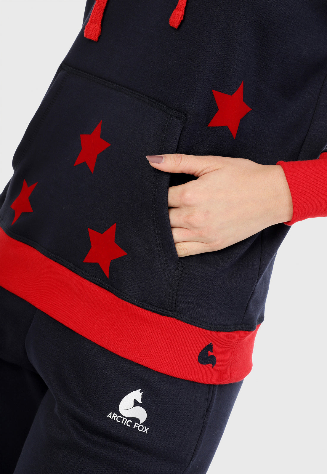 Detalle en bolsillos de mujer vistiendo la sudadera para mujer conjunto buzo hoodie color azul con estrellas rojas y pantalón de sudadera negro.