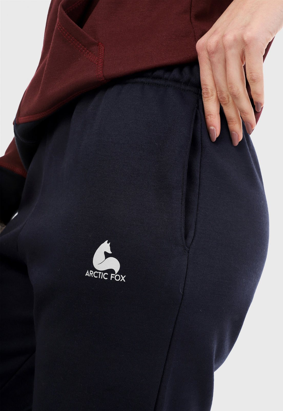 Detalle de mujer vistiendo la sudadera para mujer conjunto chaqueta hoodie vinotinto con capota forrada en azul al interior y pantalón de sudadera azul.