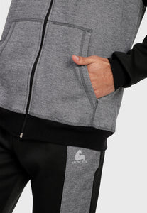 Detalle en bolsillos de hombre adulto vistiendo la sudadera para hombre conjunto chaqueta hoodie Negro y Gris con pantalón de sudadera negro y corte gris.