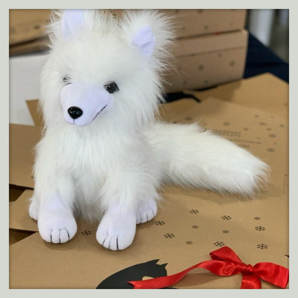 Nukappi nuestro peluche #arcticlover sobre cajas plegadas con moño rojo de Arctic Fox Colombia