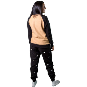 Mujer de espalda vistiendo Pijama Térmica tipo sudadera referencia Bernés de la Montaña, color tabaco y negro, con siluetas de perro Bernés en el pantalón
