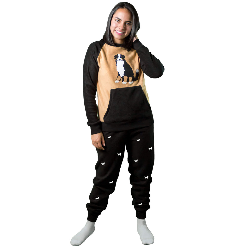Mujer vistiendo Pijama Térmica tipo sudadera referencia Bernés de la Montaña, color tabaco y negro, con siluetas de perro Bernés en el pantalón