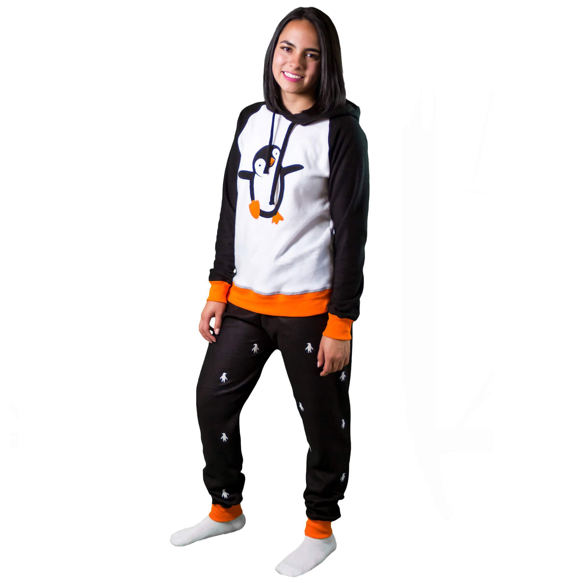 Mujer vistiendo la Pijama para Mujer referencia pingüino con siluetas de pingüino blancas estampadas en el pantalón. La pijama es de color negro, blanco y naranja con el pingüino bailarín estampado en el pecho, diseño de Arctic Fox Colombia