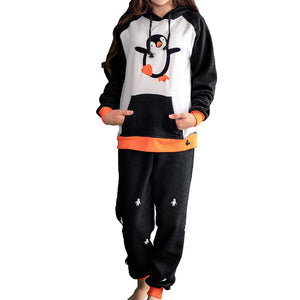 Detalle Niña de frente vistiendo la Pijama Pingüino negra y blanco con ribs naranja y capota negra con un lindo pingüino bailando en el pecho, diseño de Arctic Fox Colombia