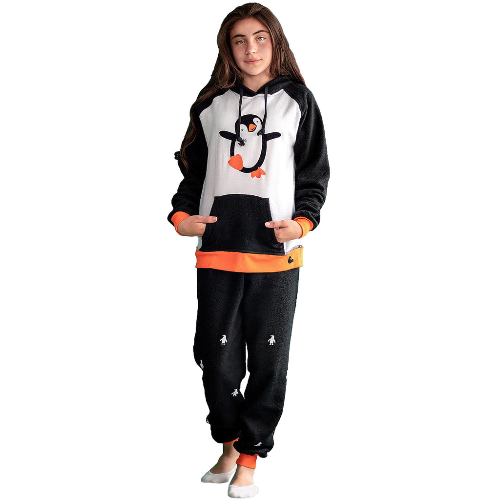 Niña de lado vistiendo la Pijama Pingüino negra y blanco con ribs naranja y capota negra con un lindo pingüino bailando en el pecho, diseño de Arctic Fox Colombia