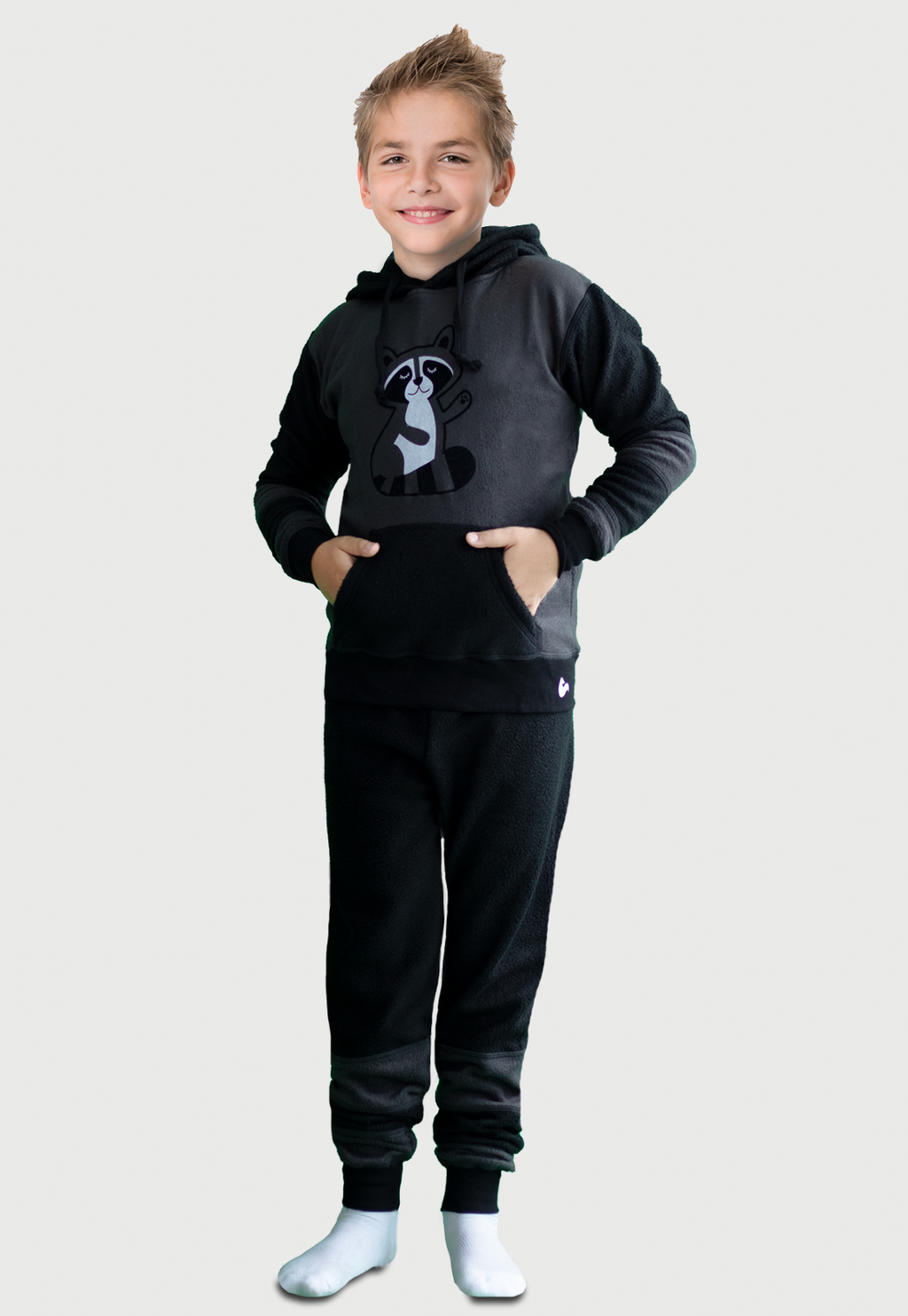 Niño cuerpo entero de lado vistiendo la Pijama Mapache negra y gris con un lindo mapache estampado en el pecho, diseño de Arctic Fox Colombia