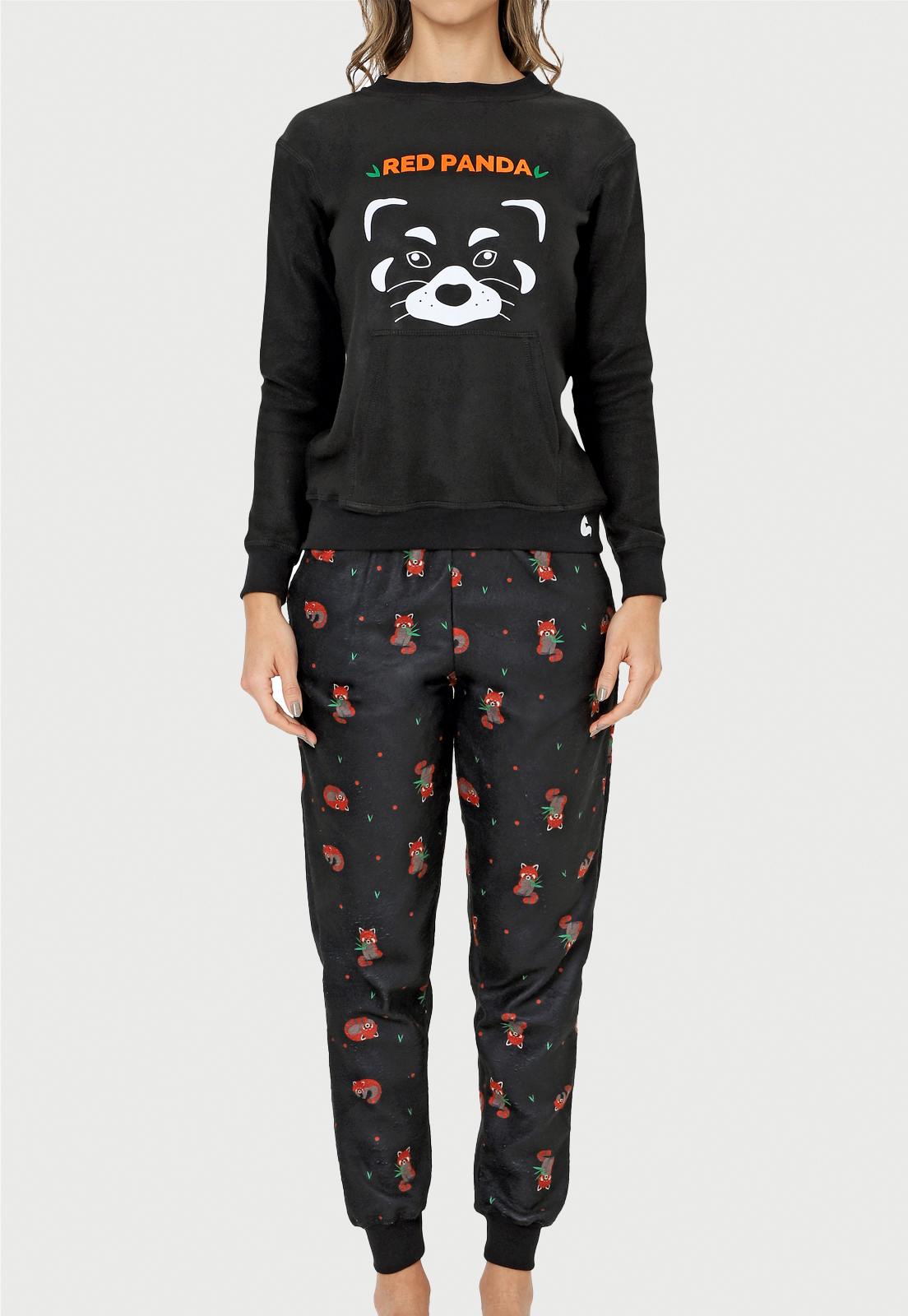 una joven usando una pijama de saco negro con la cara de un panda rojo en el centro y una grase en naranja que dice red panda, el pantalon tiene varios panditas rojos 