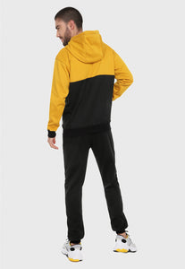 Hombre adulto visto de espalda vistiendo la sudadera para hombre conjunto buzo hoodie Mostaza y Negro Corte Inglés con pantalón de sudadera negro.