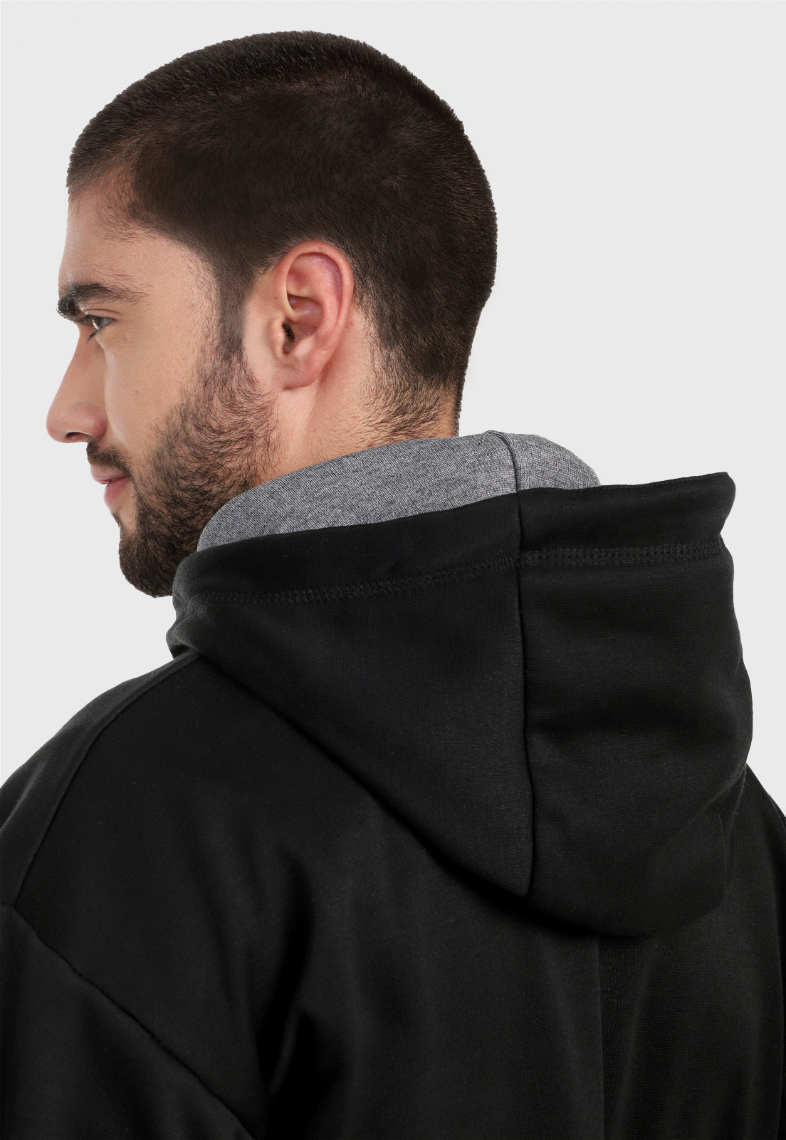 Detalle en capota de hombre vistiendo el buzo hoodie negro y gris para hombre con capota forrada gris.