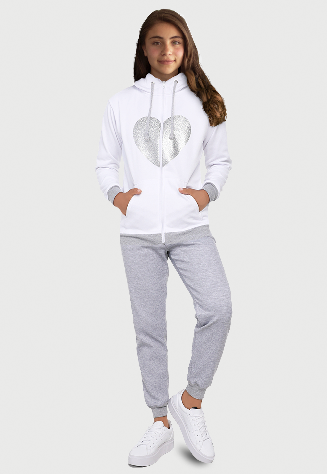 Una jovencita usando una sudadera blanca con pantalon gris jaspé, lleva estampado un corazón de escarcha, tiene cremallera  