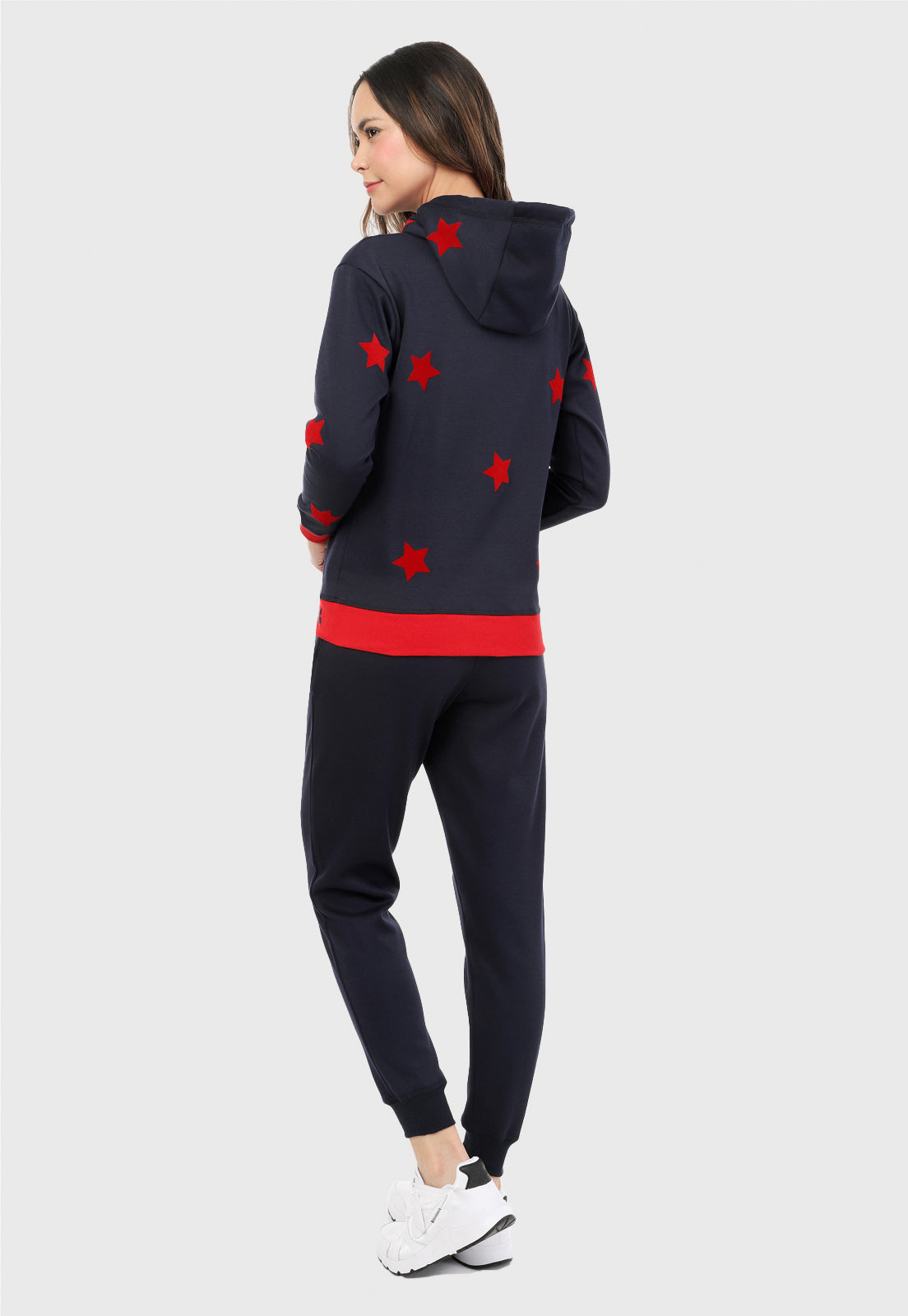 Mujer de espalda vistiendo la sudadera para mujer conjunto buzo hoodie color azul con estrellas rojas y pantalón de sudadera negro.