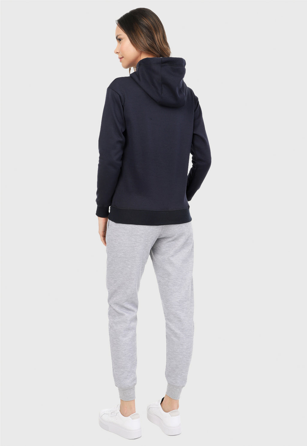 Mujer vista de espalda vistiendo la sudadera para mujer conjunto buzo hoodie azul navy con capota forrada en algodón perchado blanco y pantalón de sudadera gris jaspe.