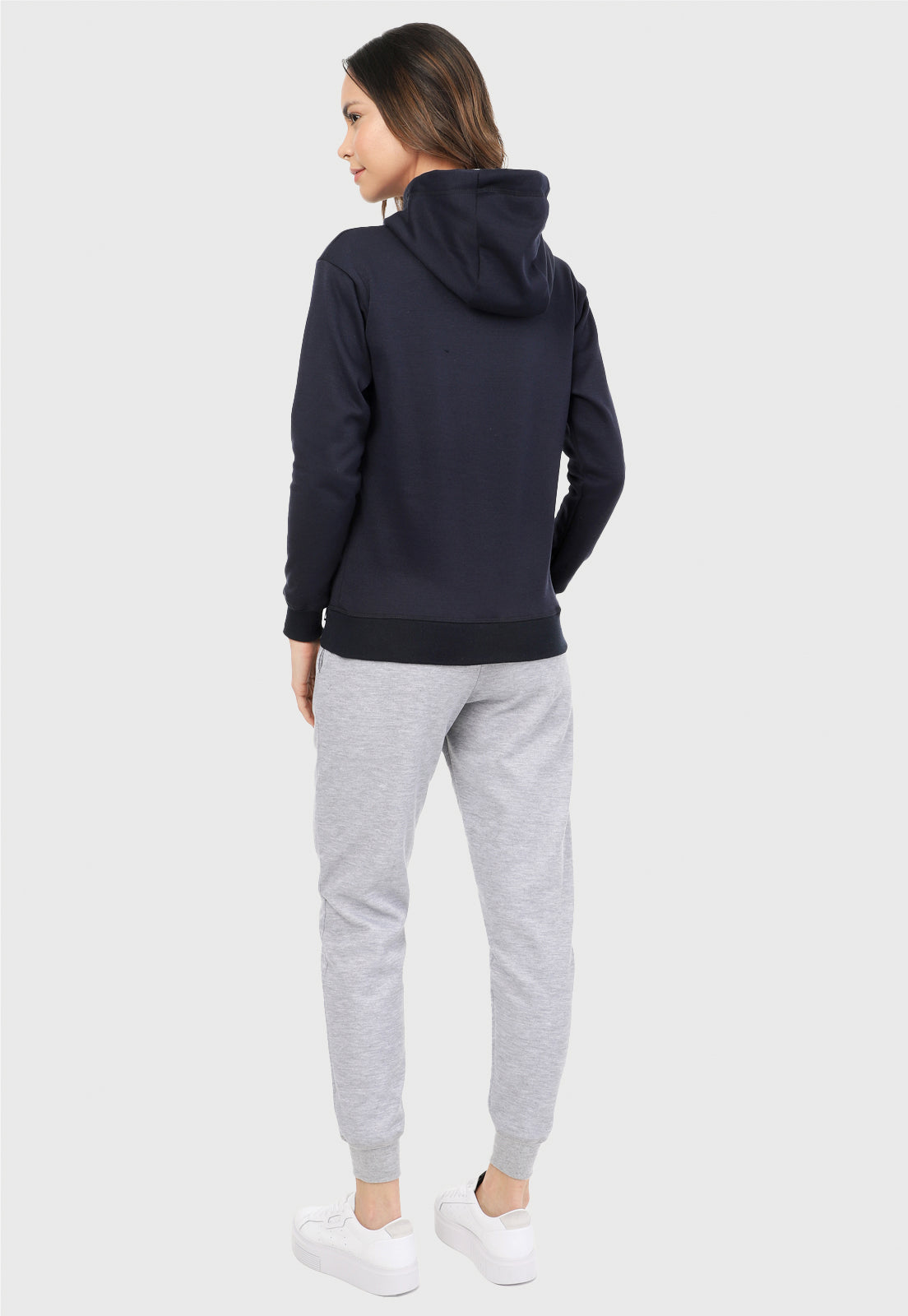 Mujer vista de espalda vistiendo la sudadera para mujer conjunto buzo hoodie azul navy con capota forrada en algodón perchado blanco y pantalón de sudadera gris jaspe.