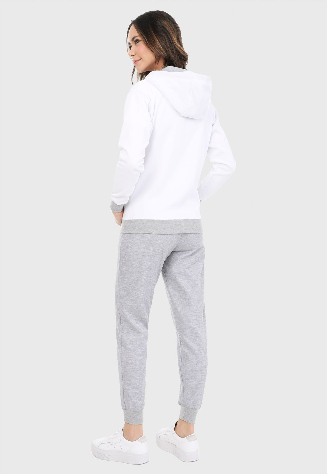 Mujer de espalda vistiendo la sudadera para mujer conjunto chaqueta hoodie blanco y gris con corazón brillante y pantalón de sudadera gris.