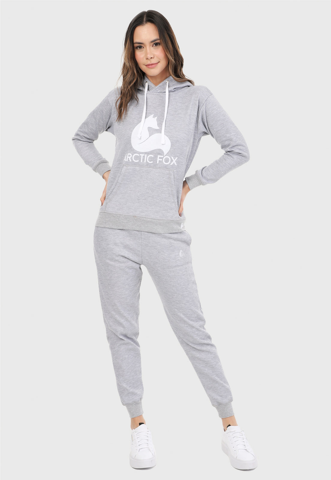 Mujer vistiendo la sudadera para mujer conjunto buzo hoodie y pantalón de sudadera gris jaspe. Lleva el zorro de Arctic Fox estampado en blanco al frente del buzo.
