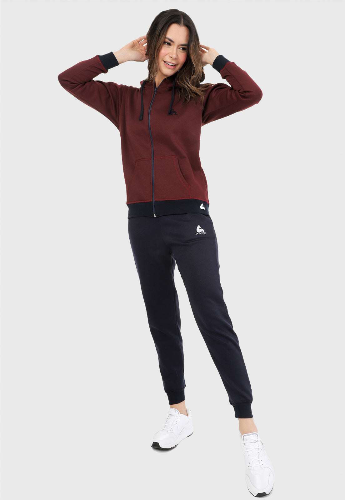 Mujer vistiendo la sudadera para mujer conjunto chaqueta hoodie vinotinto con capota forrada en azul al interior y pantalón de sudadera azul.