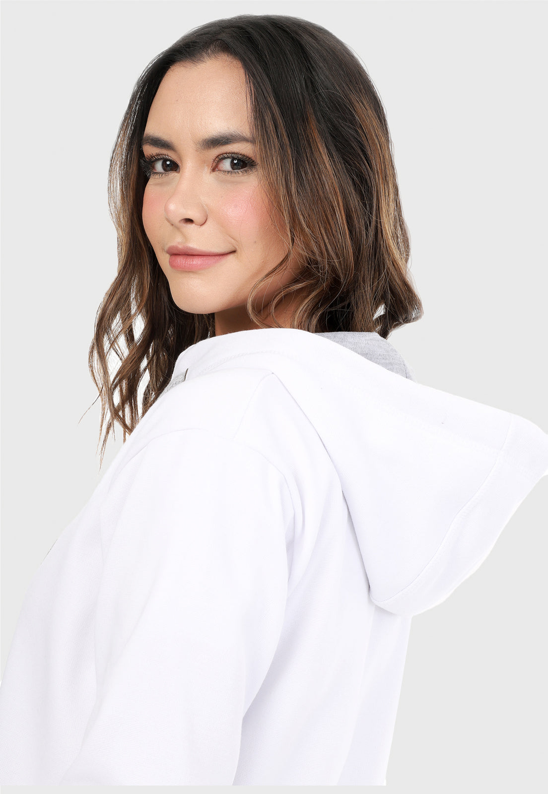 Detalle de mujer vistiendo la chaqueta hoodie blanco y gris con corazón brillante.