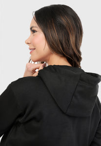 Detalle de mujer vista de espalda vistiendo la sudadera para mujer conjunto buzo hoodie negro con cerezas brillantes, ribs vinotinto en puño y cintura y pantalón de sudadera negro.