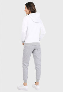 Mujer vista de espalda vistiendo la sudadera para mujer conjunto buzo hoodie color blanco con corazón plateado y pantalón de sudadera gris.