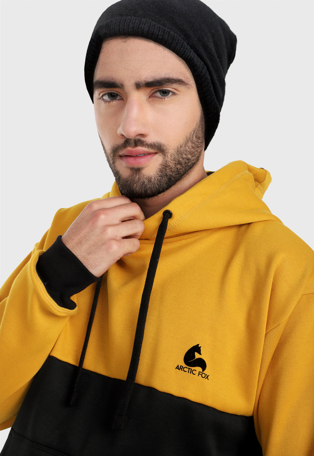 Detalle de hombre vistiendo el buzo hoodie mostaza y negro para hombre corte inglés.