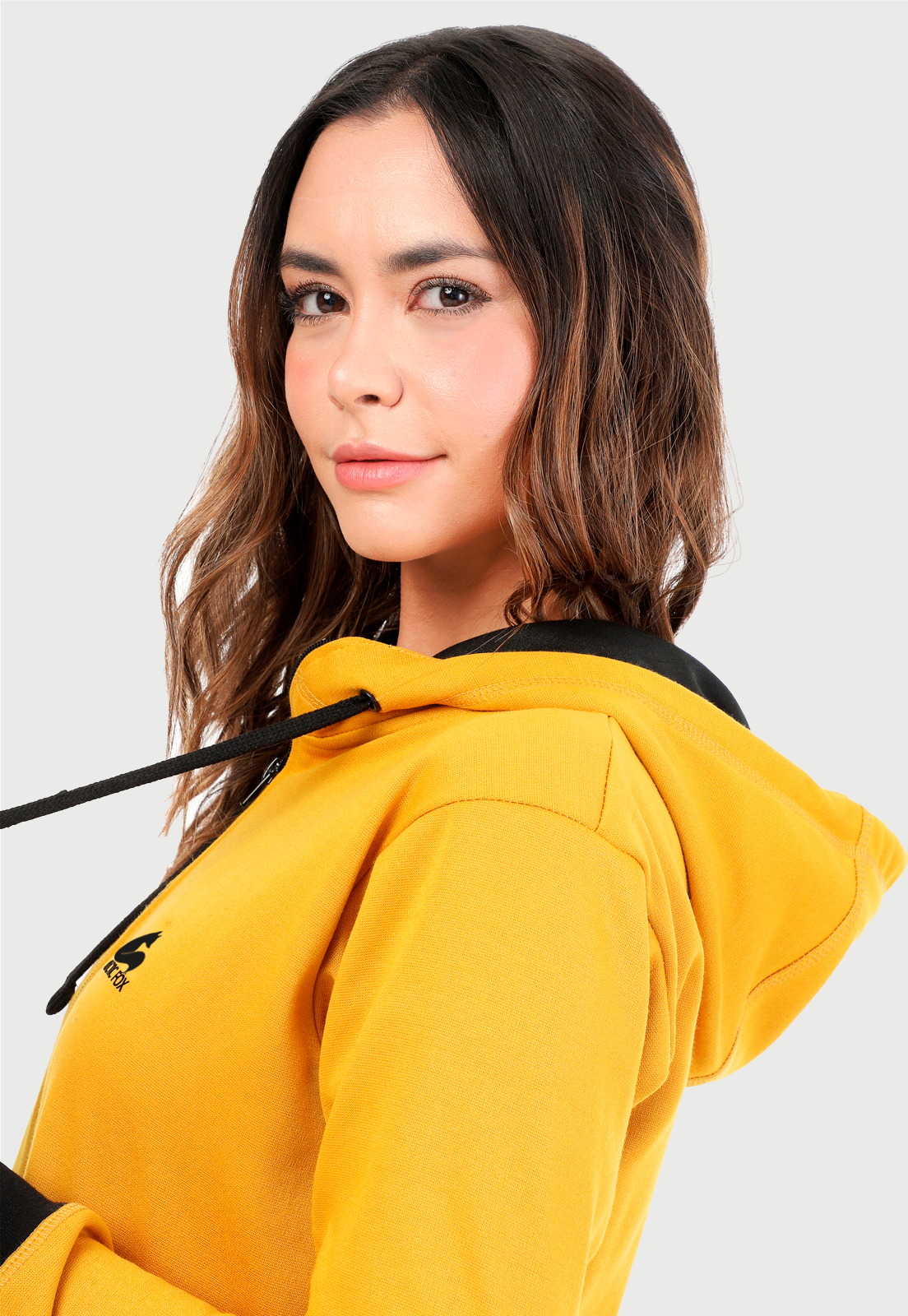 Detalle de mujer vistiendo la chaqueta hoodie mostaza y negro.